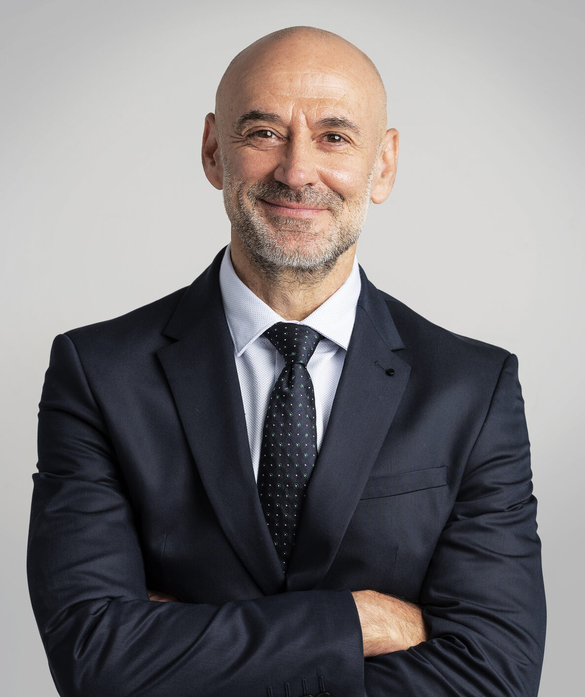 Portrait of caucasian business man looking at camera and smiling. Confident mature male professional is in suit. He is against gray background.